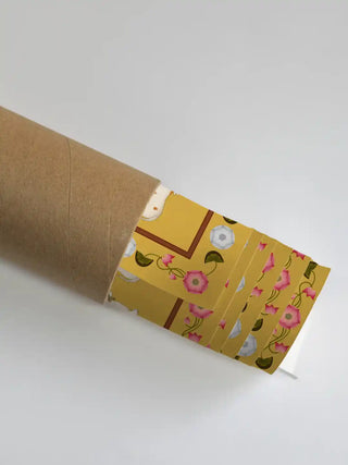 Close up of the Shrinathji Pichwai floral border and lotus motifs emerging from a rolled packaging shipping tube.