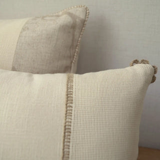 A macro view of the hand-looped taupe crochet scalloped tab on the corner of the Linen Poet pillow panel.