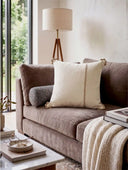 The Linen Poet embroidered cushion cover styled elegantly on a plush contemporary velvet sofa panel.