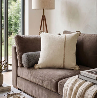 The Linen Poet embroidered cushion cover styled elegantly on a plush contemporary velvet sofa panel.