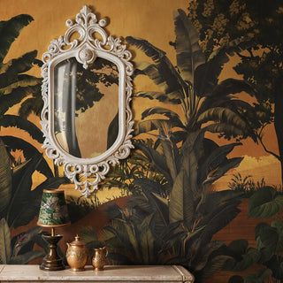 A sun-drenched mustard tropical mural featuring palm trees styled with an ornate white Baroque mirror and vintage decor.