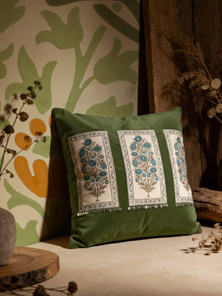 The Nayab olive green embroidered cushion styled in a warm heritage interior next to a botanical wall.