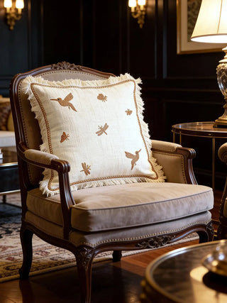 The Echo Chinoiserie Fray embroidered cushion styled on a classic wooden and velvet armchair in a luxury library.