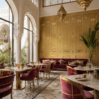 The Zellige Hall wallpaper in a grand restaurant with burgundy velvet furniture and a marble coffee table. view-restaurants
