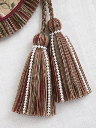 A detailed close-up view of the multi-colored braided ropes and heavy tassels accented with cascading rows of white pearls.