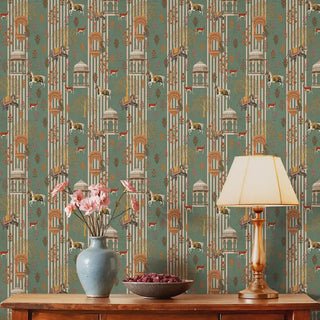 The Majestic Mewar green wallpaper installed behind a wood console styled with a ceramic vase, pink blooms and a brass table lamp view-livingroom