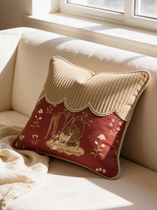 A luxury Malhar Rope and Grove cushion featuring crimson heritage motifs and a tan corded top on a cream linen sofa.