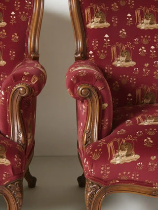 Close up of the Malhar upholstery fabric showing the intricate texture and carved wooden armrests of a luxury chair.