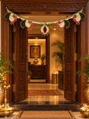 The Mangal Mayura toran across a carved wooden doorway: four peacocks with green velvet tails and pink necks, and a central anar, on a gold coin lace border.