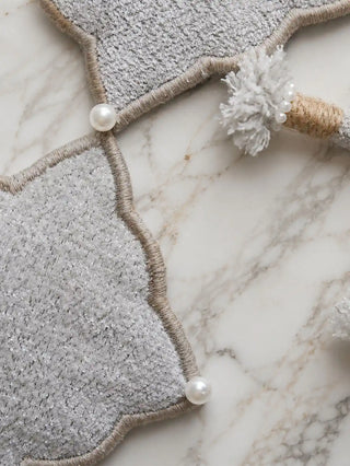 A high-resolution close-up of the shimmering gray boucle fabric panels, corded borders, and white seed pearls on the Marrakesh Moti tie back.