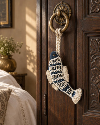 Matsya navy and ivory beaded fish charm tied to a brass ring pull on a carved walnut door knob