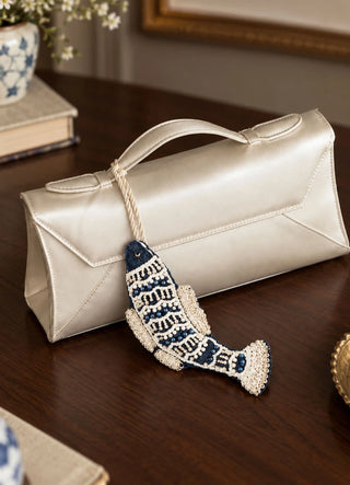 The Matsya charm in Navy & Ivory, view-clutchbag clipped onto a satin clutch handle.