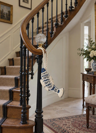 The Matsya charm in Navy & Ivory, view-stairnewel hanging from a glass newel post finial.