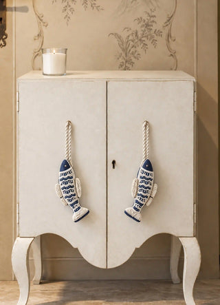 The Matsya charms in Navy & Ivory, view-cabinetpair hanging from cabinet door pulls beside a candle.