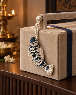Matsya navy and ivory fish charm tied to a champagne velvet box