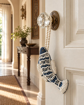 Matsya navy velvet fish charm with ivory beadwork hanging from a vintage crystal doorknob.