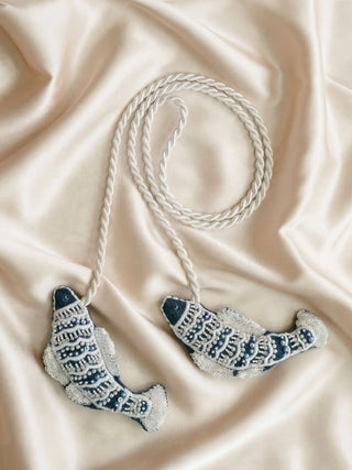 A flat-lay view of the Matsya fish tieback styled on shimmering cream silk fabric.