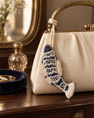 Matsya navy velvet fish charm with ivory embroidery tied to an ivory silk handbag.