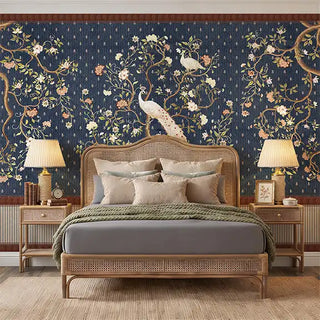 A sophisticated bedroom featuring the Mayura Blue mural behind a rattan bed frame with sage and cream linens.