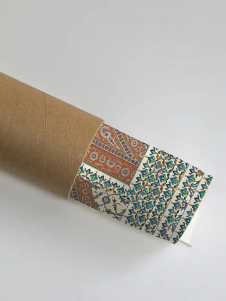 Meena Bazar wall art print in ivory and terracotta rolled in a kraft shipping tube, showing the blue and green tilework border detail.