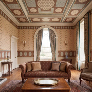 Meena Buti wallpaper on the walls of a grand formal drawing room paired with the coordinating Meena Jaal ceiling mural overhead, brown rolled-arm sofa, brass tray table, wooden floors, teal curtains, and wall sconces