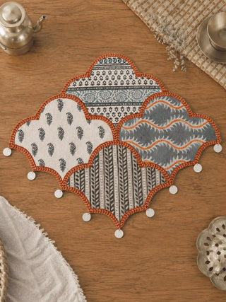 A top-down view of the Mehrab table mat showcasing its scalloped arch silhouette and intricate patchwork of traditional block prints.