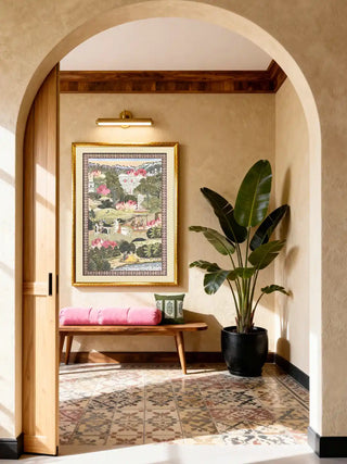A grand arched entryway featuring Mewar embroidery wall art styled with a wooden bench and large tropical plant.
