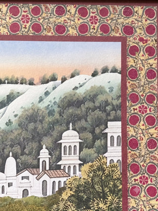A high-resolution close-up of the traditional crimson floral border, white palace towers, and green hills in the Mewar artwork.