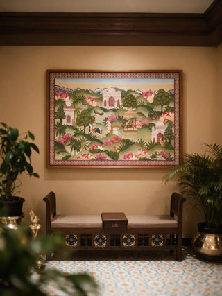 The Mewar Indian wall art in Green & Brown, framed and hung view-entryway above a wooden bench flanked by potted plants.