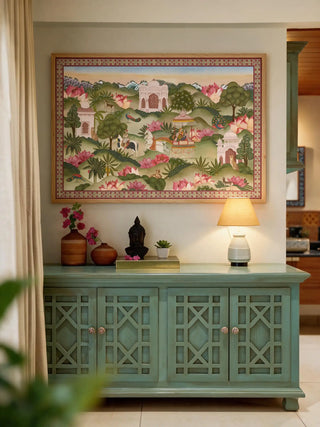 The Mewar Indian wall art in Green & Brown, framed and hung view-entryway above a sage-green console with a Buddha bust and lamp.