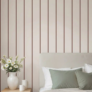 Beige wallpaper with slim vertical brown stripes behind a modern bed and soft green cushions, adding a subtle yet elegant touch.