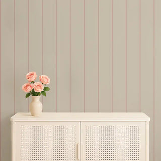 Beige wallpaper with subtle pink stripes styled with a cream console and a vase of pink roses for a delicate and fresh setting.