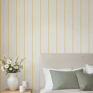 Soft yellow and cream striped wallpaper behind a modern bed with sage green cushions, creating a fresh and inviting look.