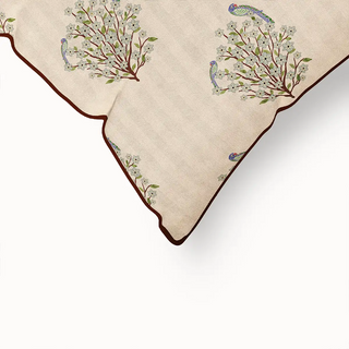 A close-up of the "Mithoo Pipin" cushion cover's corner, highlighting the neat piped edge and the intricate details of the bird and branch pattern.