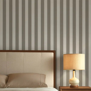 Bedroom styled with Modern Black & Grey Wide Stripe Wallpaper Roll, featuring alternating bold black and soft grey vertical stripes, paired with a beige headboard and bedside lamp.