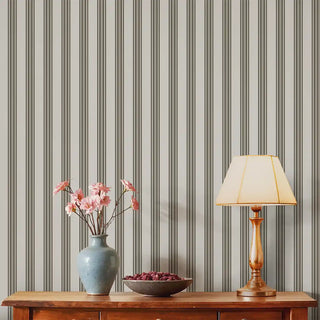 Modern Black & Grey Wide Stripe Wallpaper Roll used in a living room setup, complementing a wooden console table, ceramic vase with pink flowers, and warm lighting.