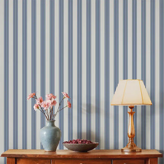 Living room wall covered with Modern Blue & Grey Wide Stripe Wallpaper Roll, paired with a wooden console table, ceramic vase with pink flowers, and a classic lampshade for a balanced interior look.