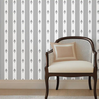 Modern Charcoal & White Arrow Stripe Wallpaper Roll in a living room, styled with a wooden cane chair, beige cushion, and light flooring for a balanced modern aesthetic.