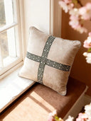 The Cross Weave geometric cushion styled on a tan window seat in a bright, sunlit room.