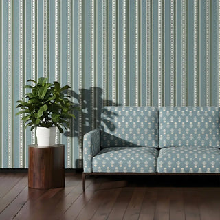 Mogra upholstery fabric in teal blue on a two-seater sofa with slim wooden legs, set against beaded blue striped walls in a living room.