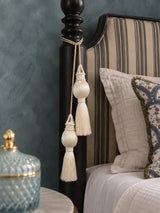 Moonlit ivory curtain tieback with two beaded tassels hanging from side of a bed