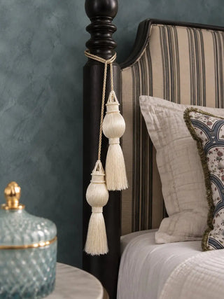 Moonlit ivory curtain tieback with two beaded tassels hanging from side of a bed