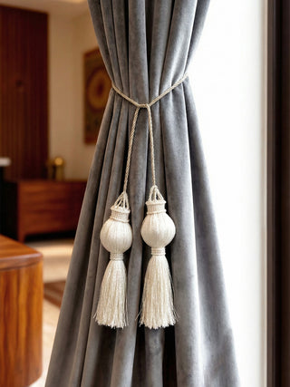 Moonlit ivory tieback with dual ornate tassels and braided cords on linen