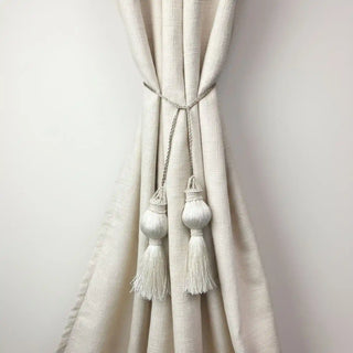 Moonlit Handcrafted Curtain Tieback secured around a cream curtain, showing the large, sphere-shaped ivory tassels.