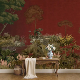 A maroon wallpaper featuring a lush tropical forest scene with tall trees, dense greenery, and flowering plants, styled behind a classic wooden console with floral decor.