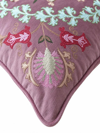 Close-up of the Naqkashi cushion cover corner showing aqua scrolling leaves, two red blooms and a pink and sage fan flower beside mauve piping.