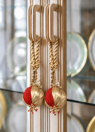 The Nar charm in Gold & Red, view-cabinethandles hanging in a matching pair from glass cabinet pulls.