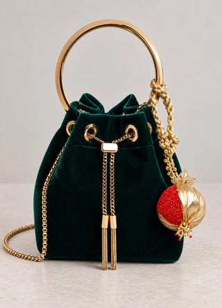 The Nar charm in Gold & Red, view-velvetbag clipped onto a green velvet bucket bag.