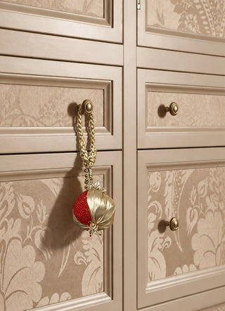 The Nar charm in Gold & Red, view-wardrobepull hanging from a floral wardrobe door handle.