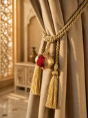 The Nar pomegranate gold curtain tieback styled around a heavy beige linen curtain panel inside a luxury heritage palace interior.